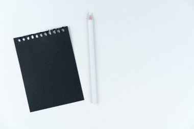 Beyaz arka planda siyah defter ve beyaz kalem var. Mukavvanın dokusu. Kara liste. Yapılandır, düzenle, boşluğu kopyala.