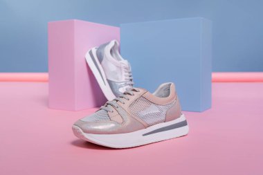 Farklı renklerde ama aynı modelden olan kadın ayakkabıları stüdyodan gelen pembe, mavi bir standın üzerinde duruyor. Tanıtım fotoğrafı.