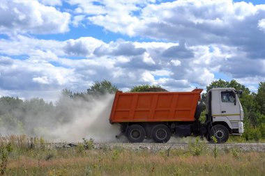 Tozlu bir kır yolunda kamyon gezintisi. Çöp kamyonu toprak yolda hızlı hareket ediyor, toz kaldırıyor. İnşaat alanına giden tozlu toprak yolda moloz yığınları olan bir kamyon..