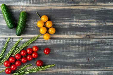 Siyah ahşap masada biberiyeli ve salatalıklı kırmızı ve sarı kiraz domatesleri. Boşluğu kopyala