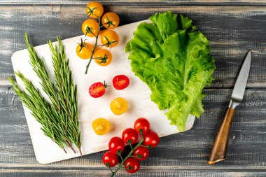Biberiye, salata ve beyaz kesim tahtasındaki kiraz domatesleri. Salata için sebze hazırla.