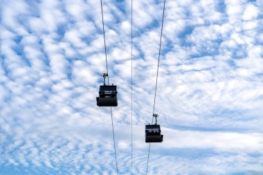 cableway cabins on a background of blue sky and white clouds in sunny summer weather clipart
