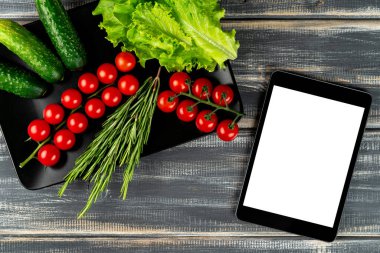 Salata, kiraz, salatalık, salatalık, marul, siyah tabakta biberiye ve tablet için hazır. Yemek tarifi. Vejetaryen menüsü.