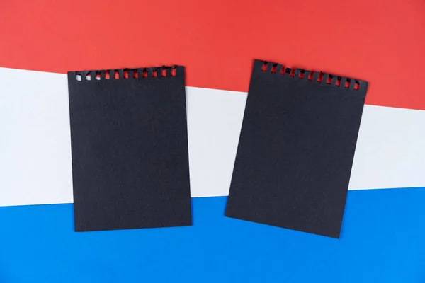 Lista negra de Holanda. Luto, prohibición, sanciones, política. hoja negra de cuaderno se encuentra en la bandera holandesa. Maquillaje, espacio de copia, patrón, textura de cartón . — Foto de Stock