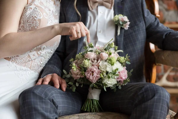 Gelin ve damat düğün buketi tutuyorlar. Yeni evliler ve gelin buketi. Düğün buketi yeni evlilerin elinde olacak. Gelin ve damat el ele tutuşun ve çiçekleri tutun.