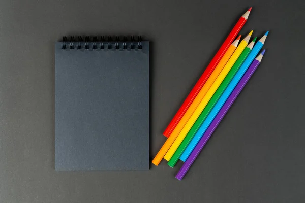 black notebook and lgbt colored pencils on black background. Mock Up Notebook of black paper and lgbt colored pencils are lying on paper background. Copy space.