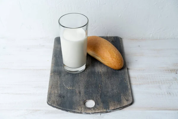 Mjölk med vete mini baguette på skärbräda. Lätt rustik frukost. — Stockfoto