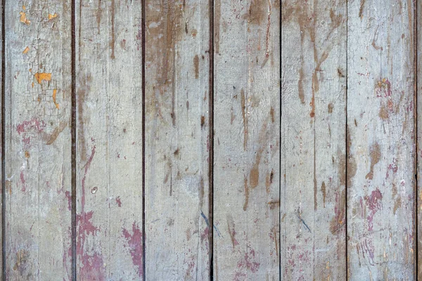 old painted wooden planks of yellow color are peeling off from time. Paint peeling off the wooden surface of the old planks. Texture of old painted wooden boards