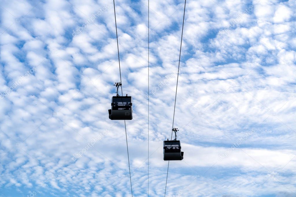 cableway cabins on a background of blue sky and white clouds in sunny summer weather