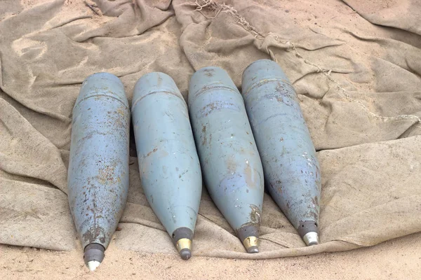Four rusty artillery shells on sand — Stock Photo, Image