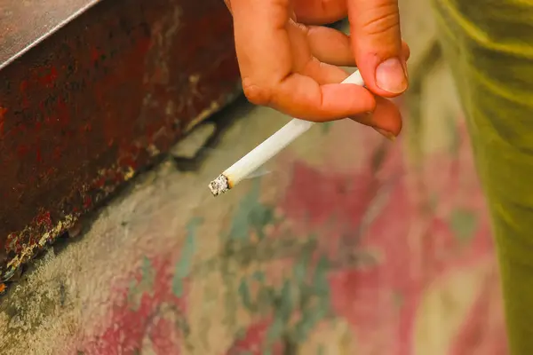 Женщина курит сигарету держит пальцами — стоковое фото