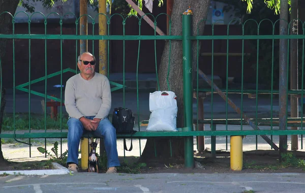 Житомир, Украина - 20 октября 2015 г.: Человек сидит на скамейке с собакой внизу — стоковое фото