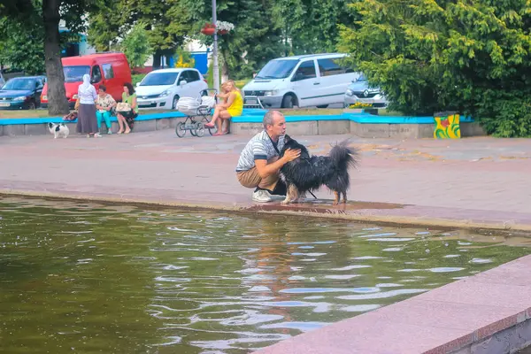Житомир, Украина - 05 сентября 2015 года: собака облизывает мужчину возле реки — стоковое фото