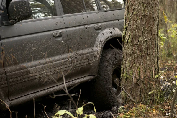 Off-road car going through deep mud holes. Detail of dirty car with filled mud - carwash concept. car wheels. dirty car wheel stands on forest road — Stock Photo, Image