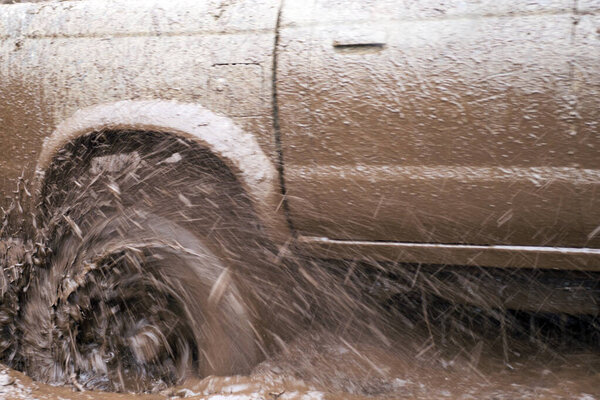 Off-road car going through deep mud holes. Detail of dirty car with filled mud - carwash concept. car wheels. dirty car wheel stands on forest road