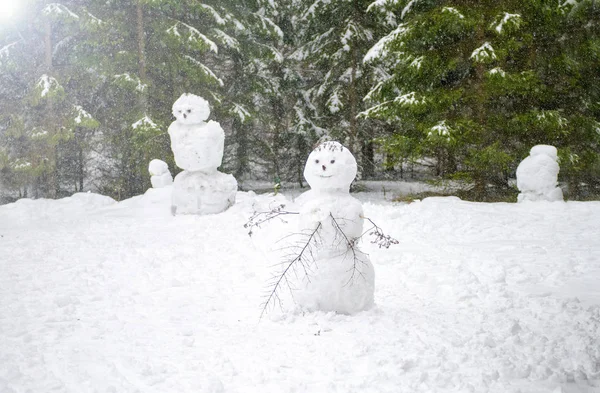Cute smiling snowman with a funny haircut is standing in the snow winter forest. little snownam made of white snow. Snowman stuck together out of the snow in the forest. Family of snowmen. smiling — Stock Photo, Image