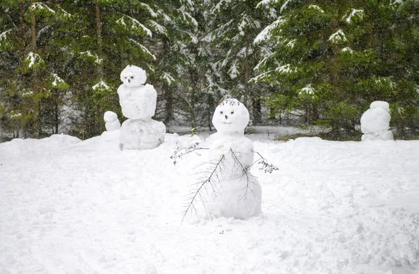 Cute smiling snowman with a funny haircut is standing in the snow winter forest. little snownam made of white snow. Snowman stuck together out of the snow in the forest. Family of snowmen. smiling — Stock Photo, Image