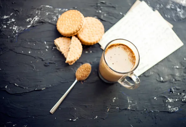 Ένα φλιτζάνι καφέ με μπισκότα και καφέ σουγκάρ. Συμβολική εικόνα. Καφές φόντο. Γλυκό επιδόρπιο. Ξύλινο φόντο. Κλείσε. Φρεσκοπαρασκευασμένο φλιτζάνι καφέ latte καφέ σερβίρεται με μπισκότα σοκολάτας σε ένα — Φωτογραφία Αρχείου