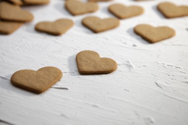 Beyaz arka planda Lezzetli Kalpli Kurabiyeler. Tahta bir masada, kalp şeklinde çubuk üzerinde ev yapımı kurabiyeler. Sevgililer Günü 'nde sevgi, sürpriz hediye ve duygu konsepti olan kurabiyeler.