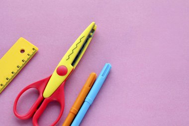 Pembe arka planda makas, cetvel ve pastel boya. Yaratıcı, modaya uygun, minimalist, okul ya da ofis çalışma alanı. Cyan arka planında sarı malzemeler var. Düz yatıyordu.