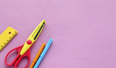 Pembe arka planda makas, cetvel ve pastel boya. Yaratıcı, modaya uygun, minimalist, okul ya da ofis çalışma alanı. Cyan arka planında sarı malzemeler var. Düz yatıyordu.