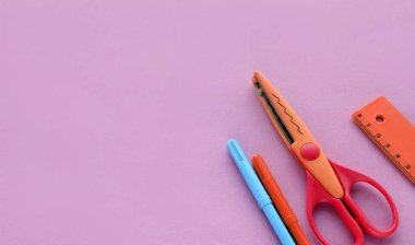 Pembe arka planda makas, cetvel ve pastel boya. Yaratıcı, modaya uygun, minimalist, okul ya da ofis çalışma alanı. Cyan arka planında turuncu malzemeler var. Düz yatıyordu.