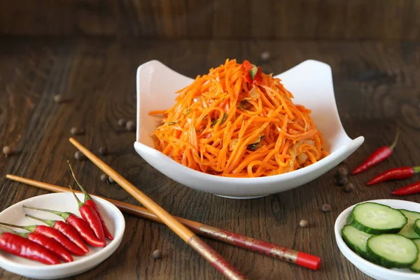 Carrot Korean meat salad with chopsticks on wooden oak table