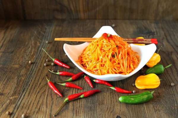 Ensalada de carne de zanahoria coreana con palillos en mesa de roble de madera —  Fotos de Stock