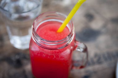 Watermelon Caipirinha andwater in a transparent glasswiht plastic coctail straw. Cocktail with Watermelon, Cachaca, Rum, Sugar and Lime.