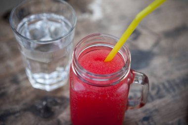 Watermelon Caipirinha andwater in a transparent glasswiht plastic coctail straw. Cocktail with Watermelon, Cachaca, Rum, Sugar and Lime.