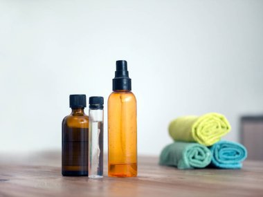 Evdeki spa prosedürleri için renkli şeffaf şişeler ve ahşap masadaki havlular. Plastik şişeleri ve mataraları geri dönüştürüyorum. Güzellik ürünleri ve tıbbi cilt bakımı için el yapımı essentia yağları