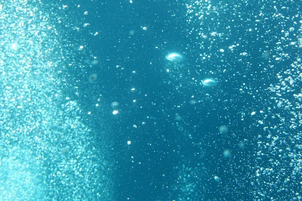 Blue ocean waves from underwater with bubbles. Light rays shining through. Great blue water bubbles for backgrounds.