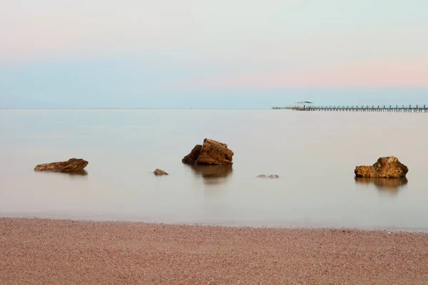Розовый Закат Над Спокойным Морем Камни Переднем Плане Камни Море — стоковое фото