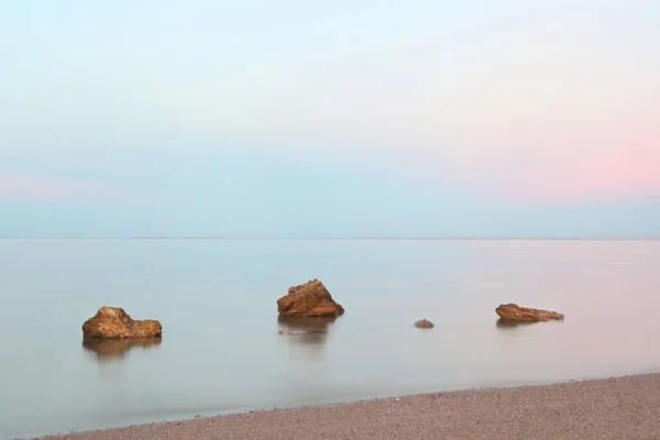 Розовый Закат Над Спокойным Морем Деревянные Камни Переднем Плане Камни — стоковое фото