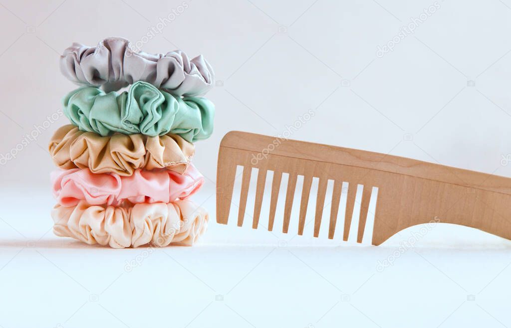 Wooden hairbrush and Lot of Colorful silk Scrunchies isolated on white. Luxury Hairdressing tools and accessories. Hair Scrunchies, Elastic HairBands, Bobble Sports Scrunchie Hairband