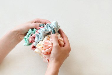Kadınların elinde bir sürü renkli ipek parşömen izole edilmiş beyaz arka plan. Kuaför aletleri ve aksesuarlar. Saç tokaları, elastik saç bantları, kızlar için Bobble Sports Scrunchie Saç bandı. Boşluğu kopyala