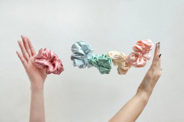 Bir sürü süzülen renkli ipek parşömen kadınların ellerinde izole edilmiş beyazlar. Kuaför aletleri ve aksesuarlar. Saç tokaları, elastik saç bantları, uçan ya da düşen saç tokası kızlar ya da kadınlar için.