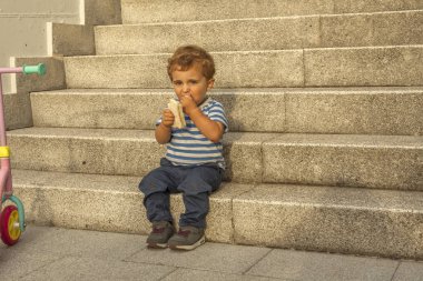 Tam çekim portre sevimli bebek çocuk taş sta oturup bir aperatif olması