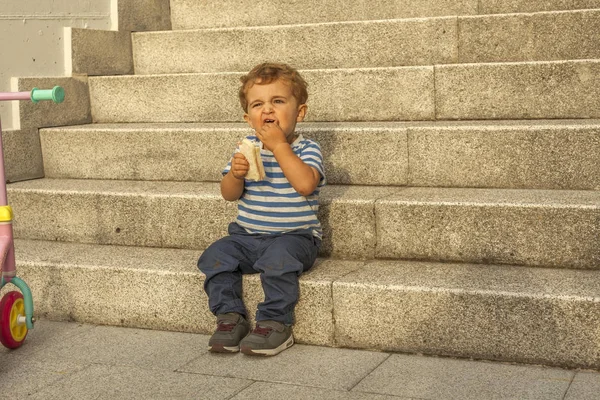 石の sta に座っておやつを持つ完全なショット肖像画かわいい男の子 — ストック写真
