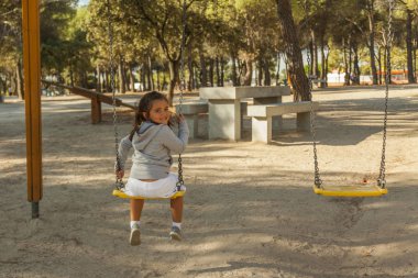 Arka görünümü Gülen Kız parkta salıncakta eğleniyor