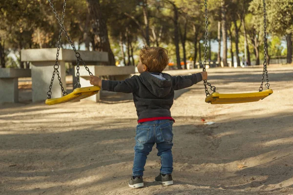 Visão traseira menino se divertindo com o balanço no playground — Fotografia de Stock