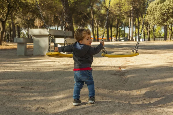 Visão traseira menino se divertindo com o balanço no playground — Fotografia de Stock