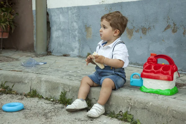 Tiro completo retrato bonito bebê menino ter um lanche sentar no sidew — Fotografia de Stock