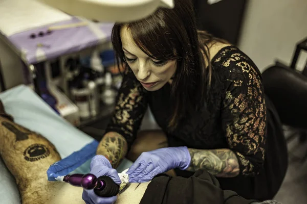 Portrait woman tattoo artist working tattoo. High angle.