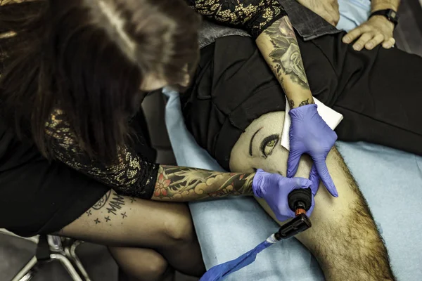 Portrait woman tattoo artist working tattoo. High angle.