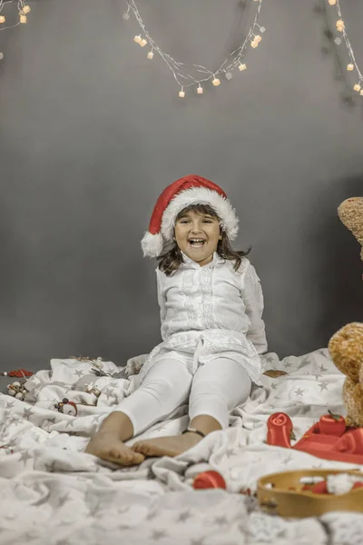 Smiley dziewczyna ubrana Santa hat w czasie świąt Bożego Narodzenia. Szare tło — Zdjęcie stockowe