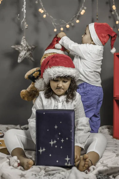 Enfants avec chapeau Santa ouverture boîte bleue. Ornements de Noël . — Photo