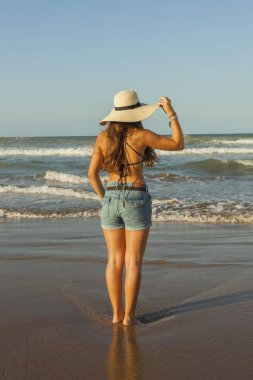 Arkasından, yaz şapka ve şort kot giyen genç kadın 
