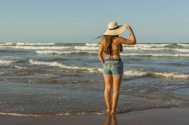 Arkasından, yaz şapka ve şort kot giyen genç kadın 