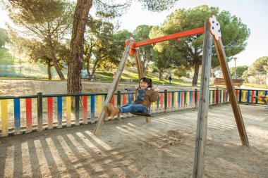 Gülümseyen kız parkta salıncakta eğleniyor